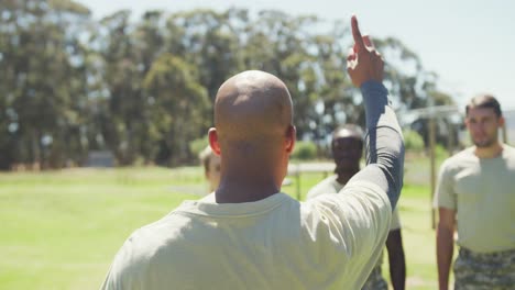 Stern-african-american-male-soldier-instructing-diverse-group-at-obstacle-course,-turning-to-camera