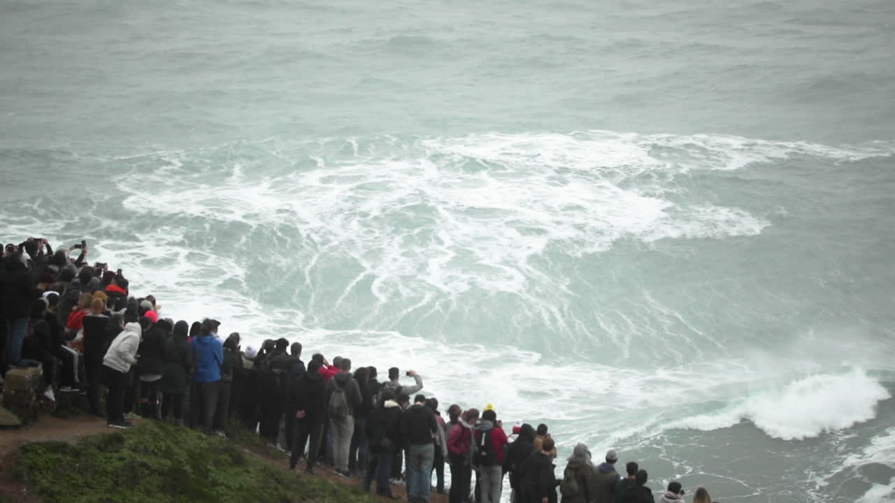 Nazare Portugal - Tourists Watching The Stunning And Famous Big Splashing Waves In Motion - Amazingly Beautiful Attraction - Wide Shot