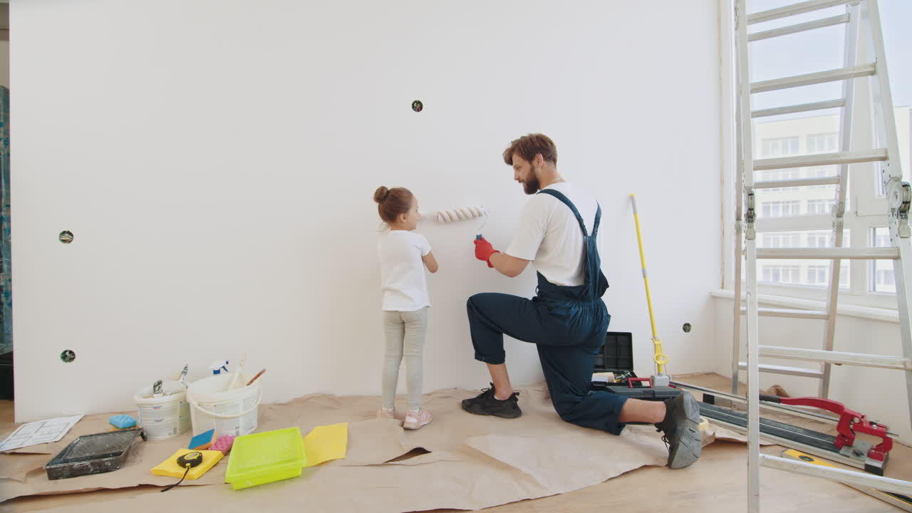 ojciec i córka malują razem ścianę.