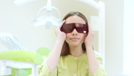 Female-dentist-dressing-up-ultraviolet-orange-safety-goggles