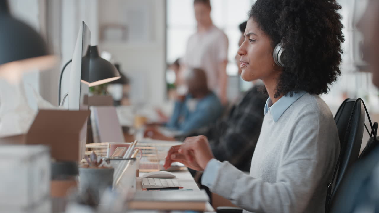 young business woman using computer typing on keyboard sending emails networking online in busy office checking smartphone