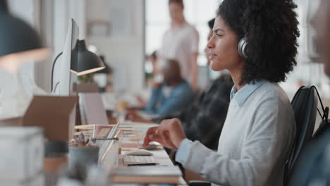 mujer de negocios joven usando computadora escribiendo en el teclado enviando correos electrónicos conectándose en línea en una oficina ocupada comprobando el teléfono inteligente