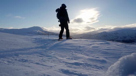 Silhouette-of-person-skiing-over-snowy-top-in-idyllic-winter-landscape,-slow-motion