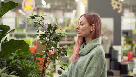 donna bionda che sceglie le piante al mercato dei fiori nel negozio di giardinaggio