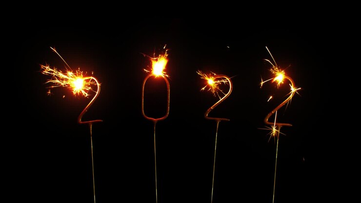 Felice Anno Nuovo 2022. Scintille e Particelle di Fuochi d'artificio su Sfondo Nero. Scintille e bagliore dorati e lucenti di fuochi d'artificio. Auguri di Capodanno e Natale. Invito, Celebrazione. Animazione in loop continuo.
