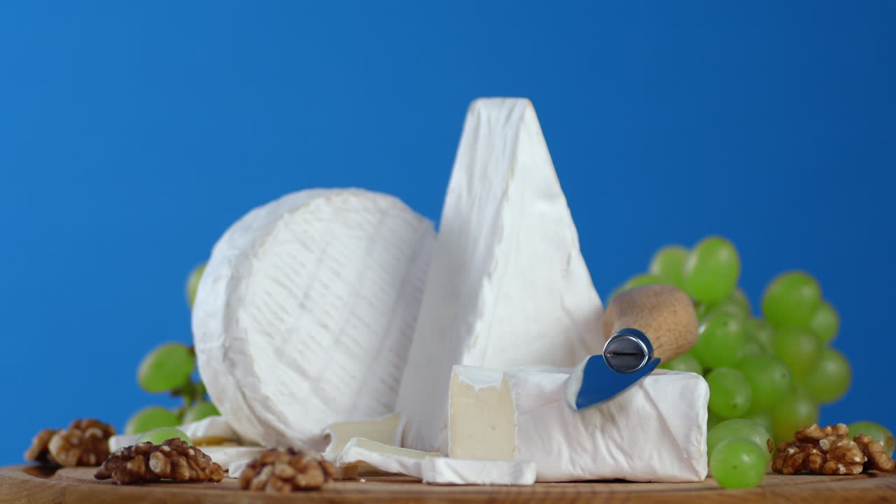 queso camembert en la tabla de cortar con las uvas girando lentamente.