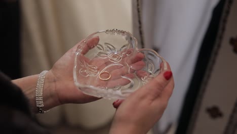 wedding rings in plate with holy water during matrimony. priest takes one ring