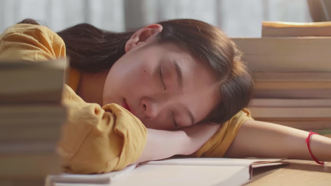 책 위에서 잠을 자는 피곤한 학생