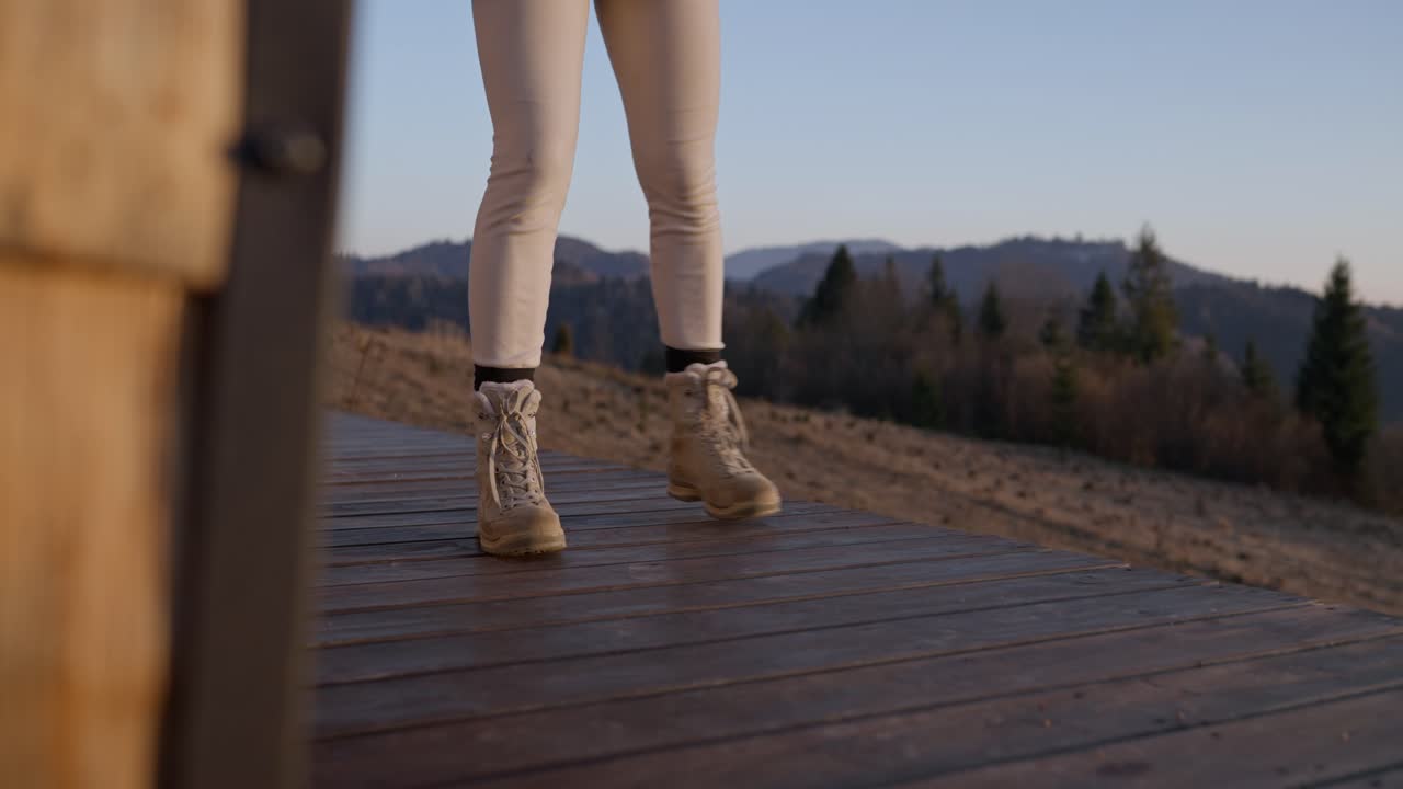 Woman sweeping wooden deck in mountain landscape