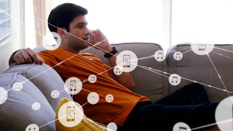 Animation-of-network-of-connections-with-icons-over-biracial-businessman-talking-on-smartphone