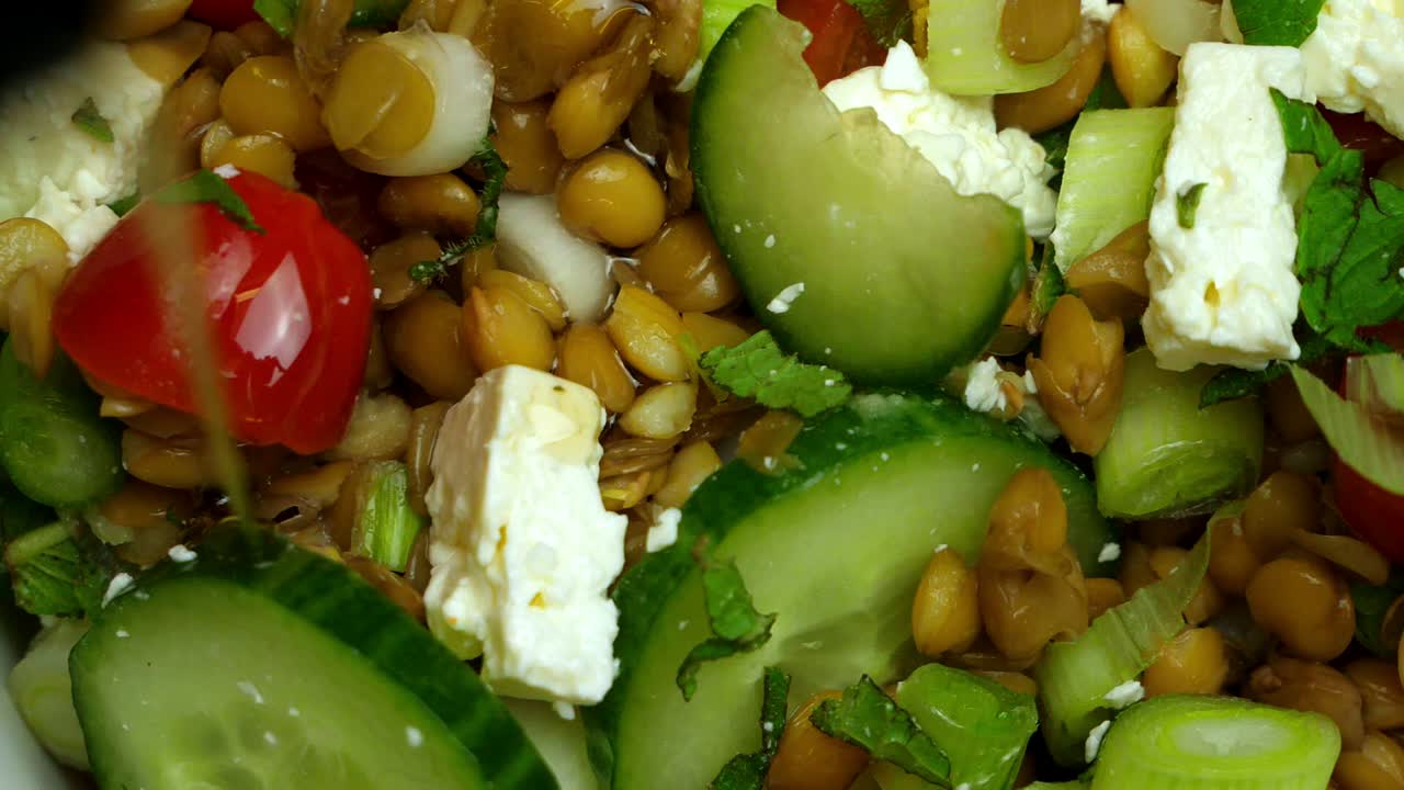 cerca de aceite rociado sobre una ensalada de queso feta y lentejas
