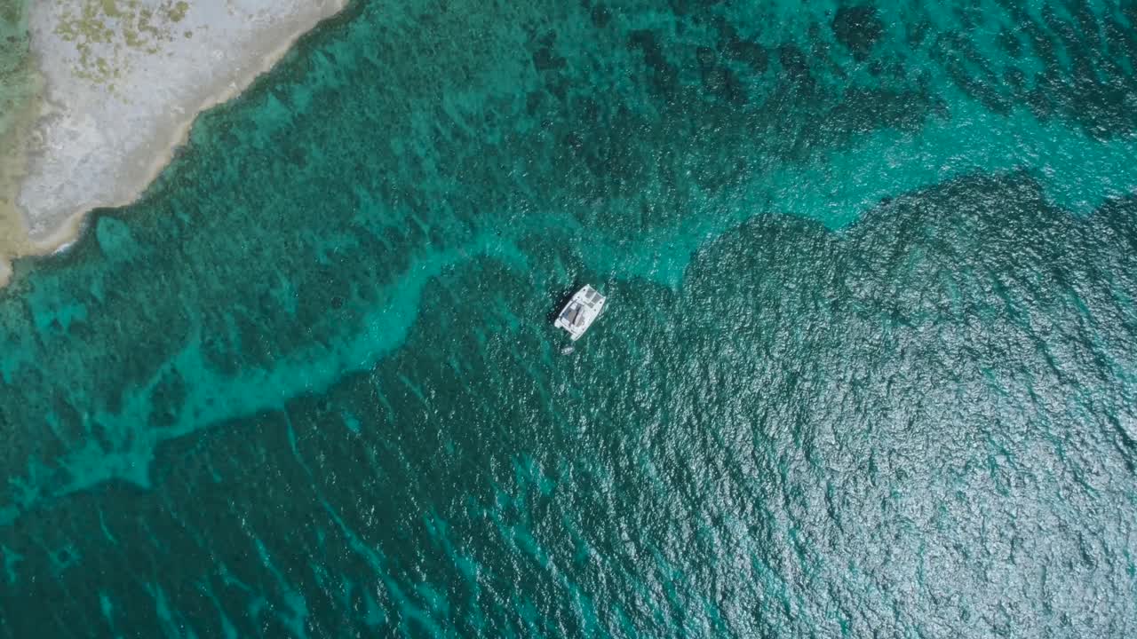 vista aérea de arriba hacia abajo de la isla desierta de las bahamas con un velero solitario y agua cristalina