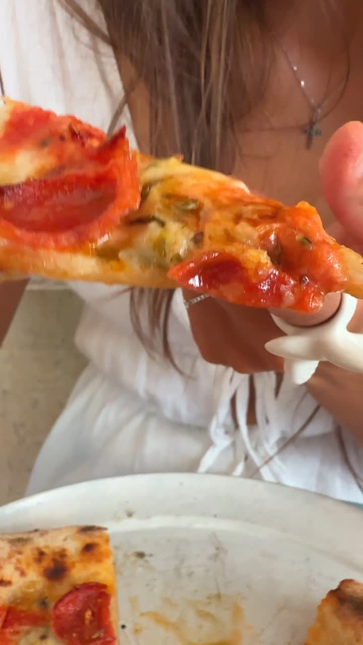 Close-up of Someone Enjoying Pepperoni Pizza
