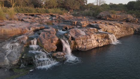 Panorámica-Aérea-Lenta-De-Una-Sección-Rocosa-En-El-Río-Komati-Con-Agua-Fluyendo-Hacia-Una-Gran-Piscina.