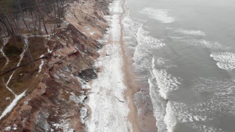 Aerial-shot-of-waves-crashing-into-sandy-beach-of-Ustka-in-winter