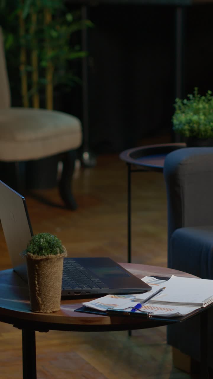 Laptop and Business Documents on Coffee Table in Empty Office Lounge