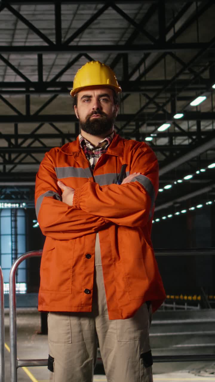 Video verticale: Professionista dell'ingegneria con casco che ispeziona le strutture metalliche in un capannone industriale
