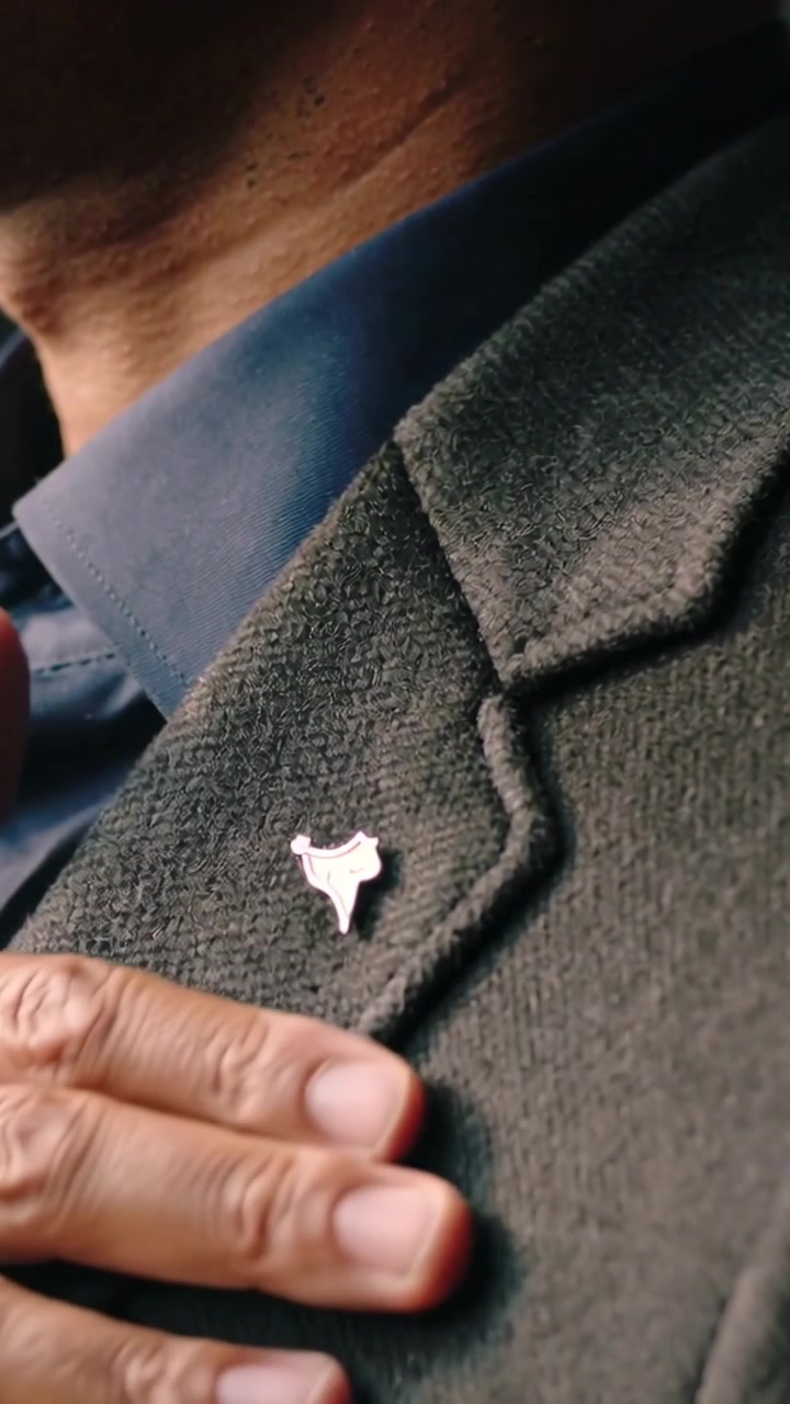 Vertical video: Raising right hand, man adjusting suit lapel in car, smoothing jacket, showing pin