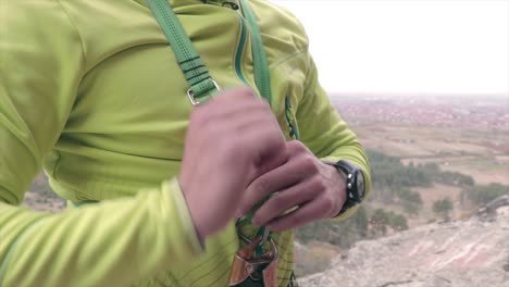 Rock-climber-securing-a-vest-before-climbing