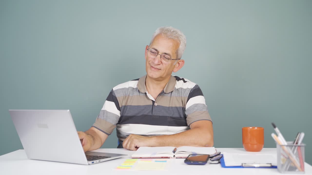 hombre mirando la computadora portátil haciendo un gesto positivo.