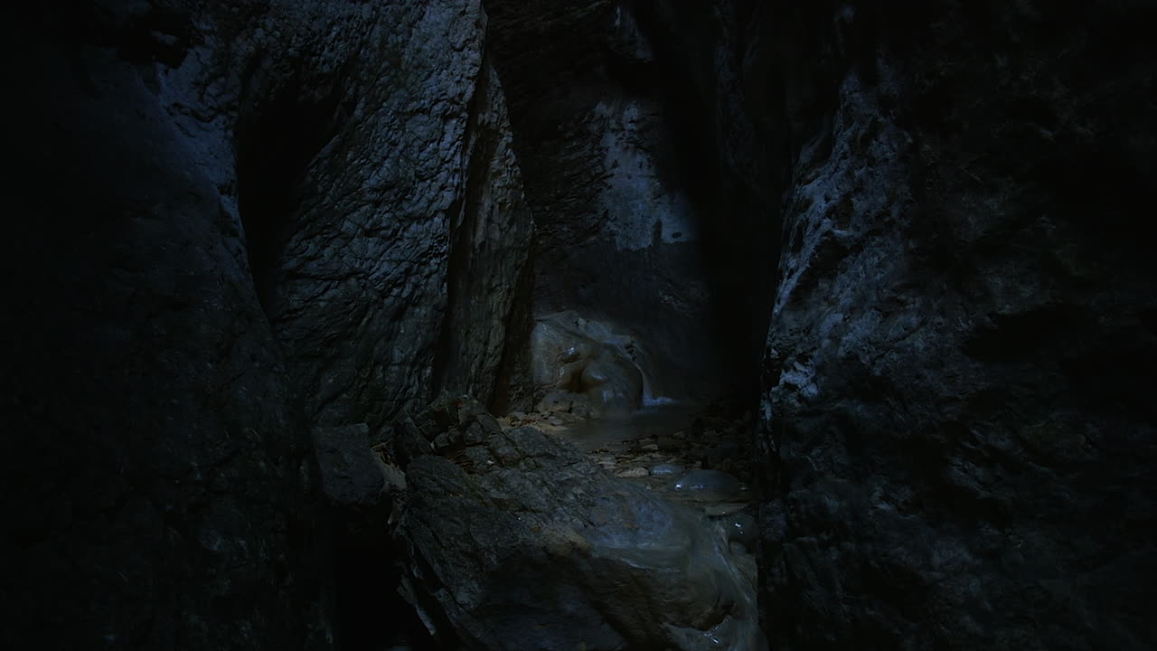 Streaming crystal clear water deep inside a narrow canyon where hardly any light penetrates