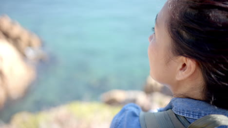 hiking in mountains, woman with backpack enjoying scenic ocean view, copy space