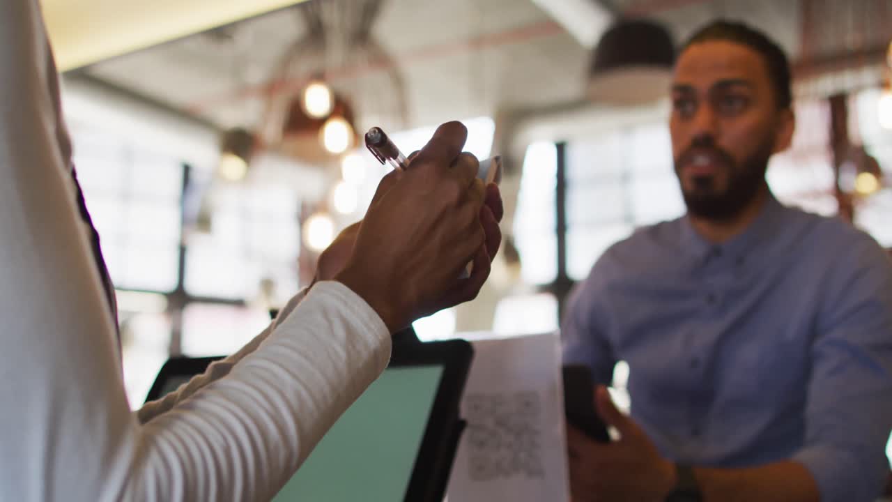 African american female cafe worker taking mixed race man order at the bar