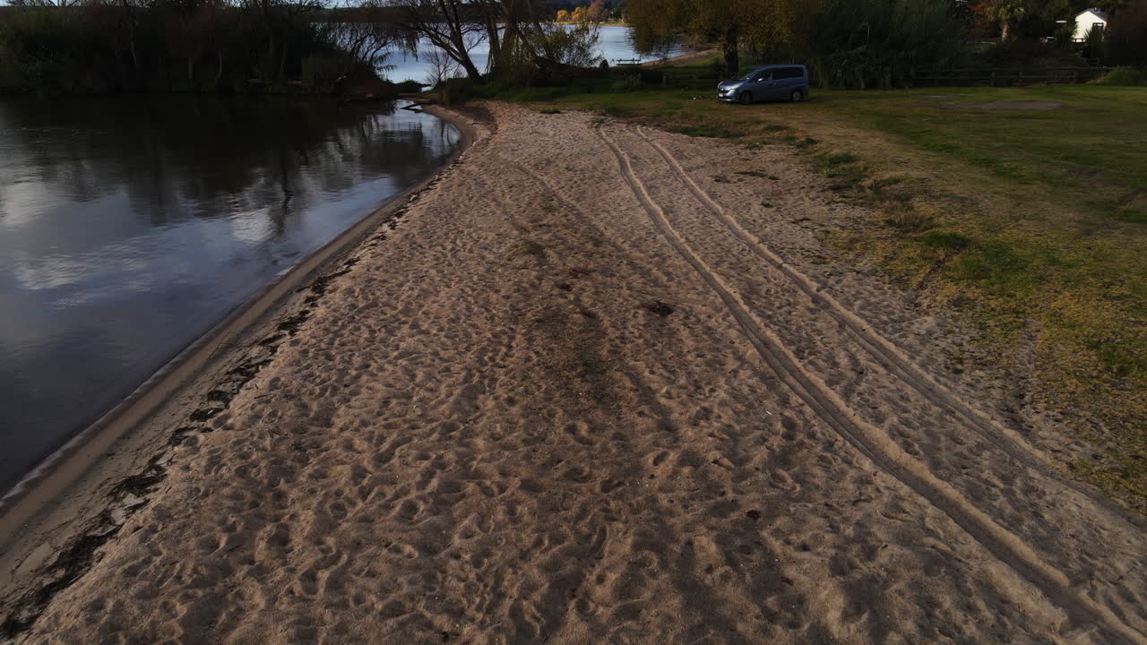 타이어 트랙과 자동차가 집과 도로 바다와 바다로 떠오르는 해변을 따라 드론 샷 스톡 비디오