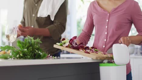 una pareja afroamericana cocinando y cortando verduras en la cocina.