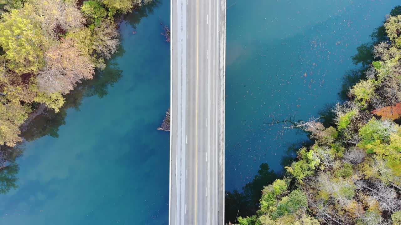 toma aérea de arriba hacia abajo de un puente sobre un río verde-azul