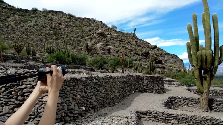 Ripresa con panoramica lenta di una giovane donna che fotografa le Rovine di Quilmes in Argentina.