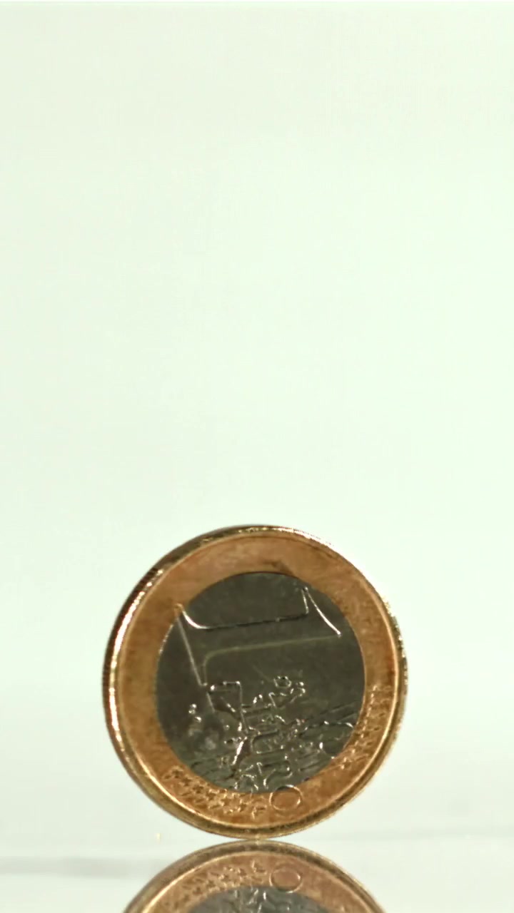 Moneta euro che gira e si bilancia su una superficie riflettente