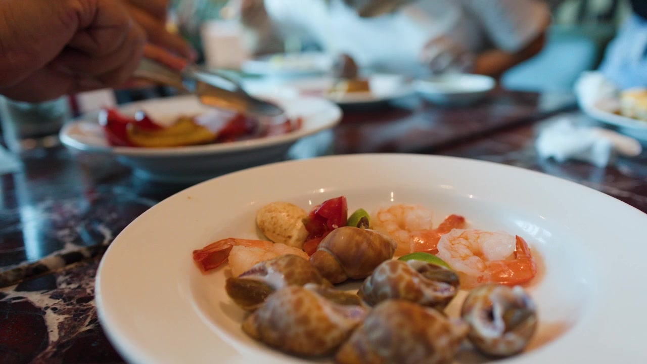 Primo piano di pinze che servono frutti di mare su un piatto bianco a un buffet di ristorante.