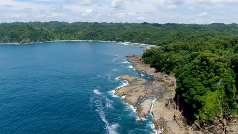 Scenic-coral-rocks-and-tropical-forest-at-Wediombo-Beach,-Indonesia,-aerial-view