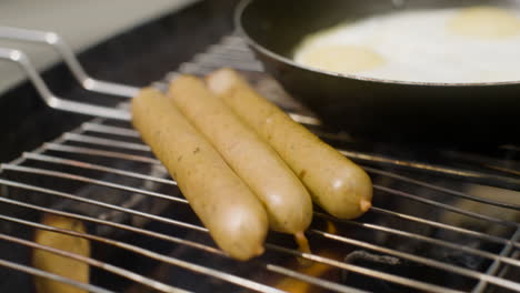 close up of sausages and pan with fried eggs on a bbq grill