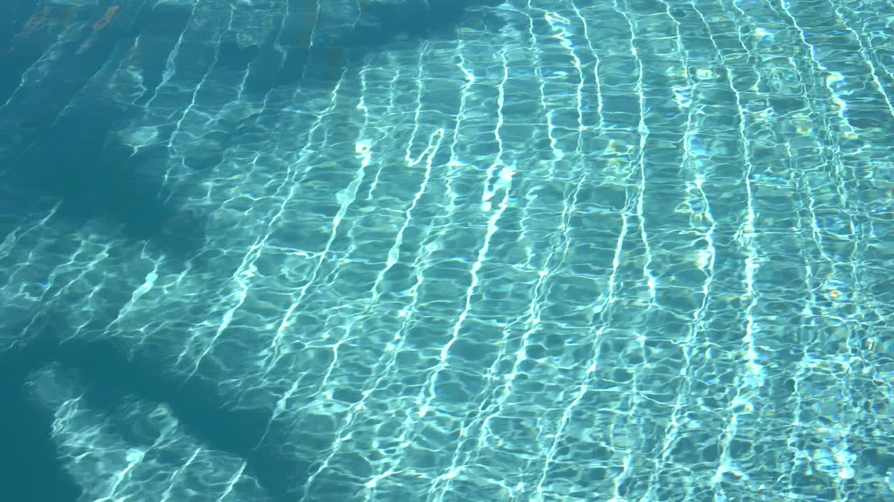 Water surface texture, Slow motion clean swimming pool ripples and wave, Refraction of sunlight top view texture sea side white sand, sun shine water background. Water Caustic Background.