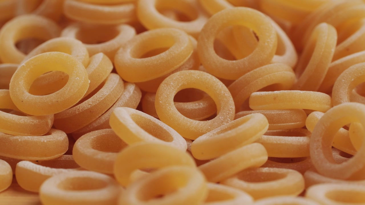 Pasta integrale biologica, maccheroni di semola di grano duro, penne rigate crude in una ciotola di legno. Filmato 4k di alta qualità