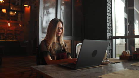 Portrait-of-a-young-girl-she-works-as-a-freelancer-in-a-cafe-drinking-a-delicious-hot-Cup-of-coffee-from-text-send-mail