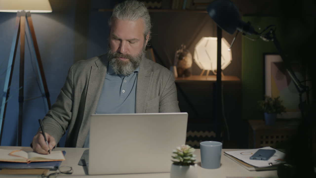 Middle-aged man working late at night in his home office
