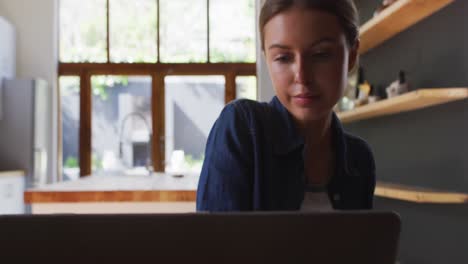 mujer usando una computadora portátil en la cocina