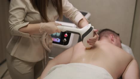 aesthetician perform laser hair removal on a man's back in a professional clinic