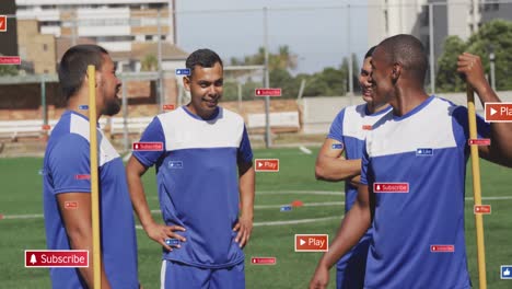 animation of social media icons over team of diverse male soccer players discussing on sports field