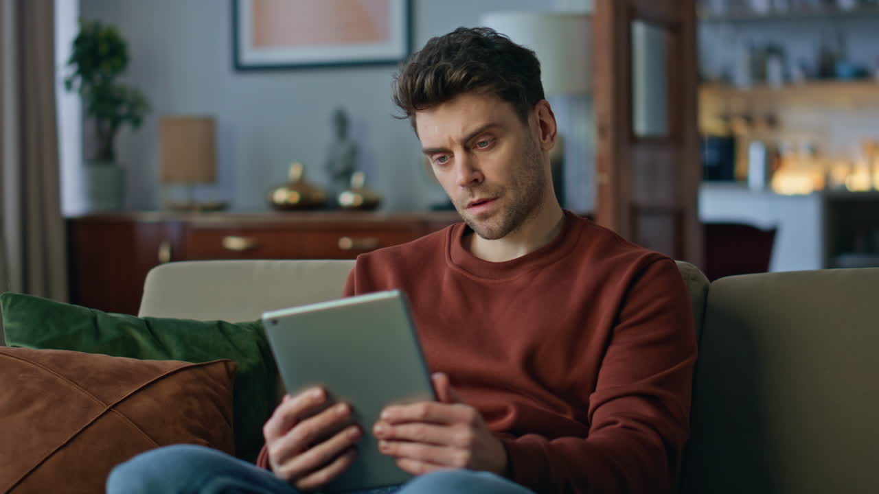 Pensive businessman browsing tablet website at home couch close up. Man thinking