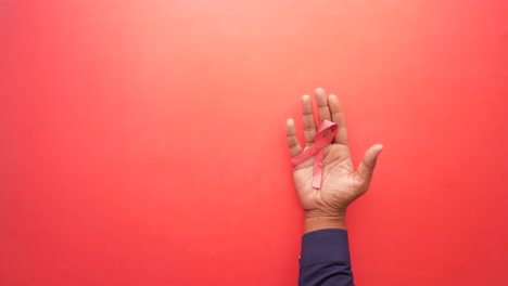 Hand-holding-red-hiv-ribbon-top-down