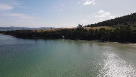 La-Antena-De-Drones-Se-Mueve-Hacia-Atrás-Desde-La-Casa-En-La-Playa-De-Arena-Con-Agua-Azul-Tropical