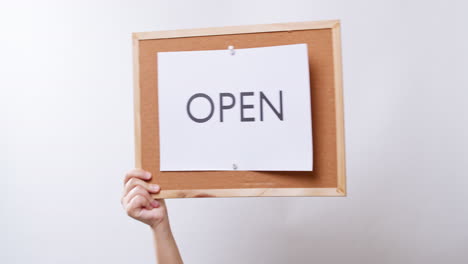 Woman's-hand-shows-the-paper-on-board-with-the-word-OPEN-in-white-studio-background-with-copy-space