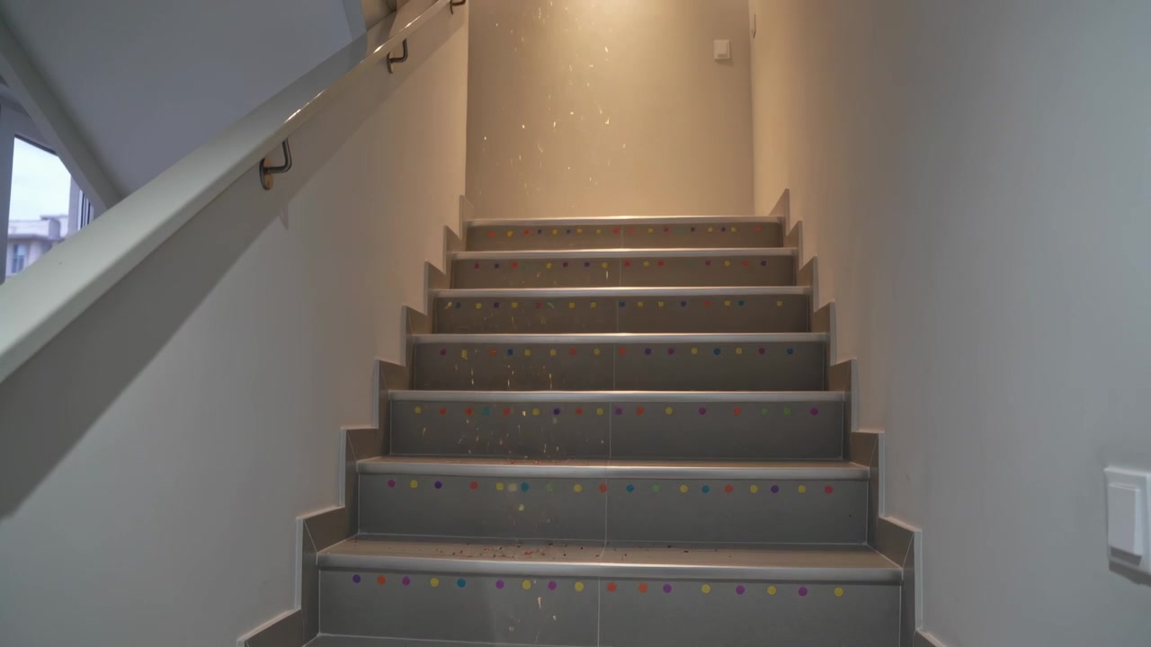 Mostrando un faretto che si accende, una scala piastrellata che si illumina con particelle che cadono e alzate a punti colorati.