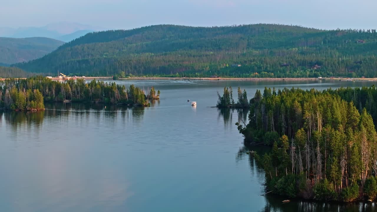 Drone panoramic overview of Grand Lake Colorado capturing forested shoreline and still water reflections under cloudy sky