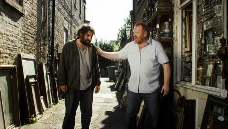 a serene stroll through an antique alley: two men explore a vintage shop surrounded by framed artwork and curiosities in bright daylight