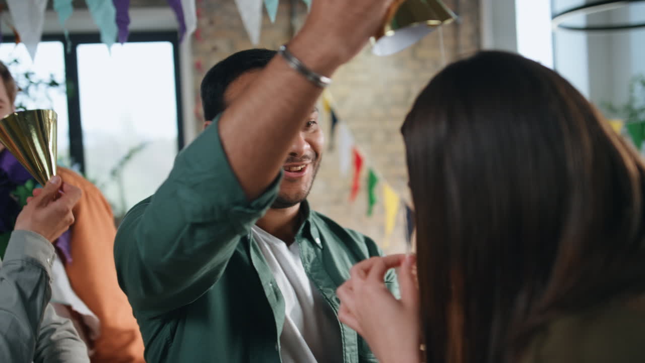 웃는 동료들이 생일파티를 위해 모자를 들고 축제를 준비하고 있습니다.